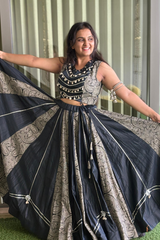 The sleek black choli is adorned with mirror embellishments and golden piping