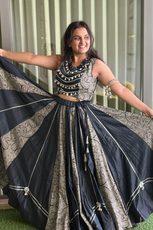 The sleek black choli is adorned with mirror embellishments and golden piping